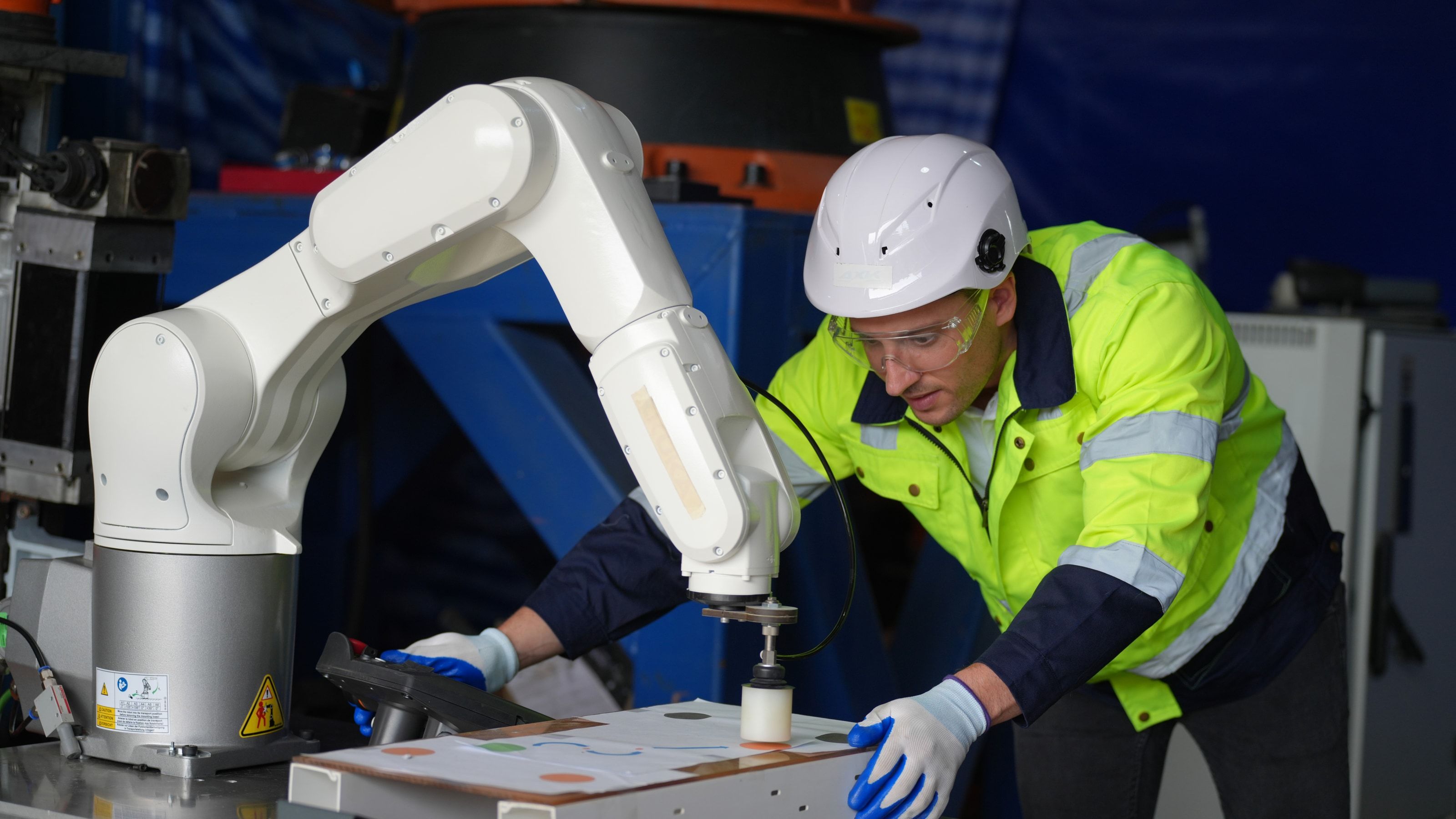Operario trabajando junto a un robot colaborativo de pequeño tamaño en una célula de producción