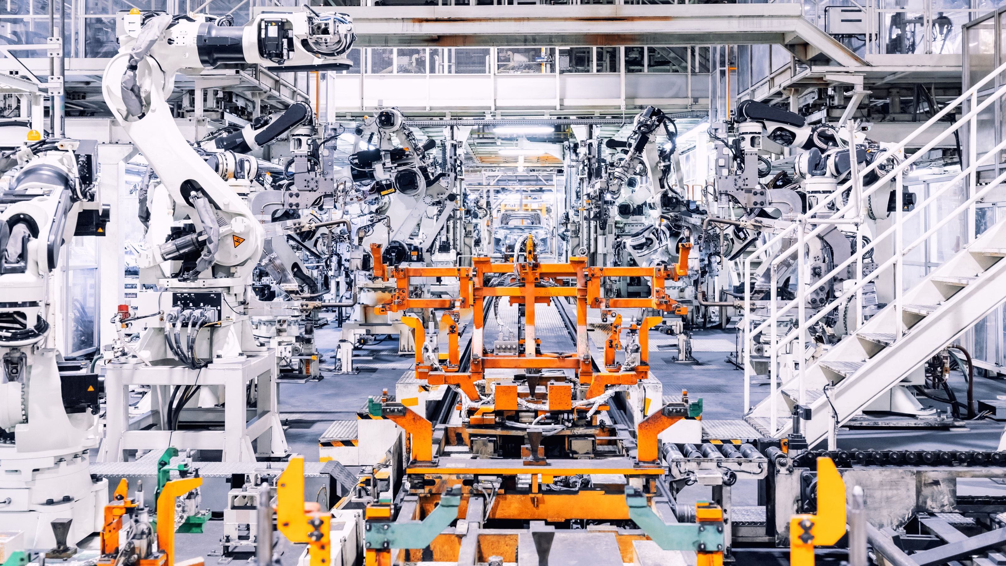Robots industriales trabajando sobre carrocerías en una línea de producción de automoción