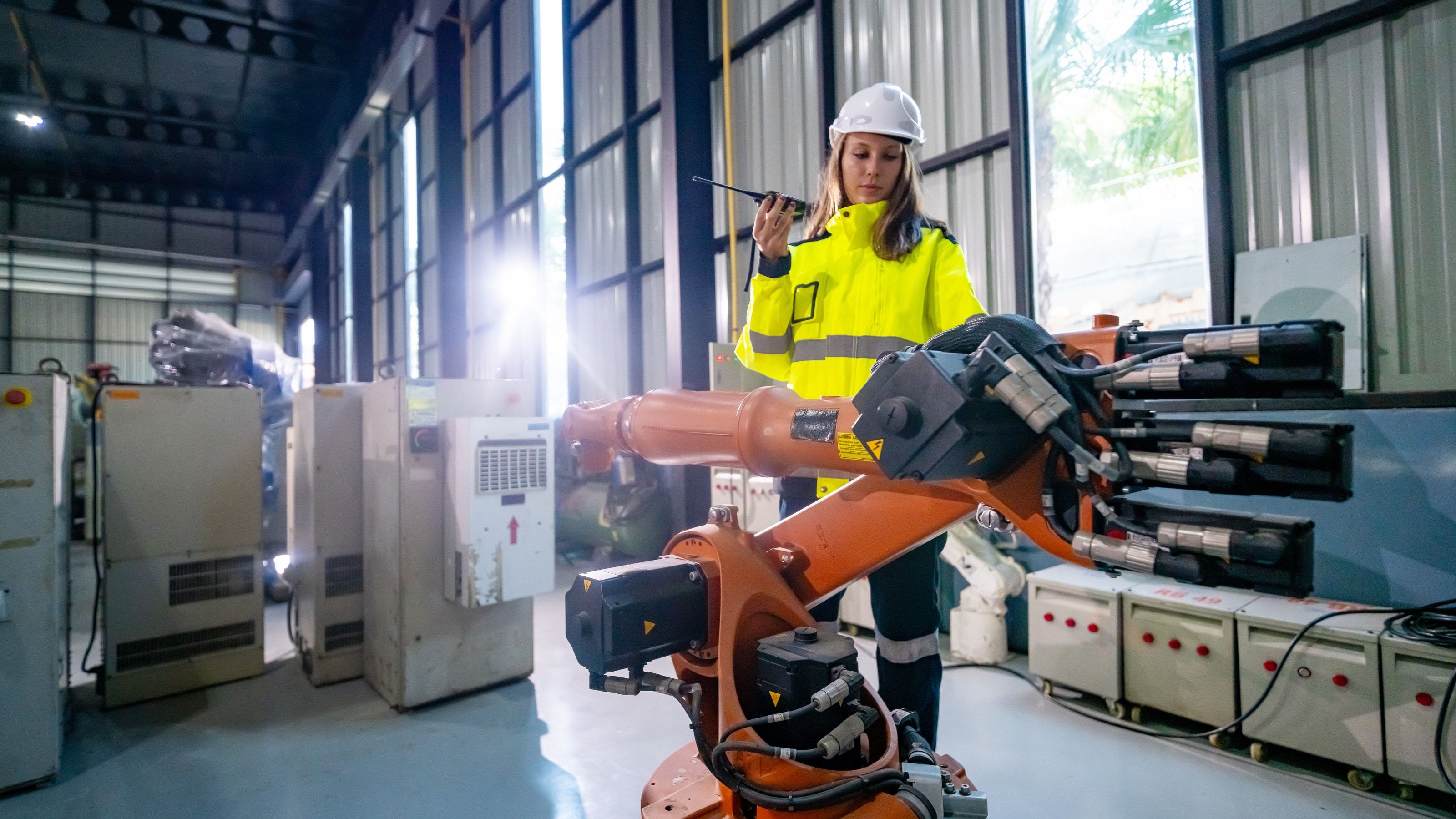 Ingeniera de planta junto a un robot industrial articulado de gran tamaño